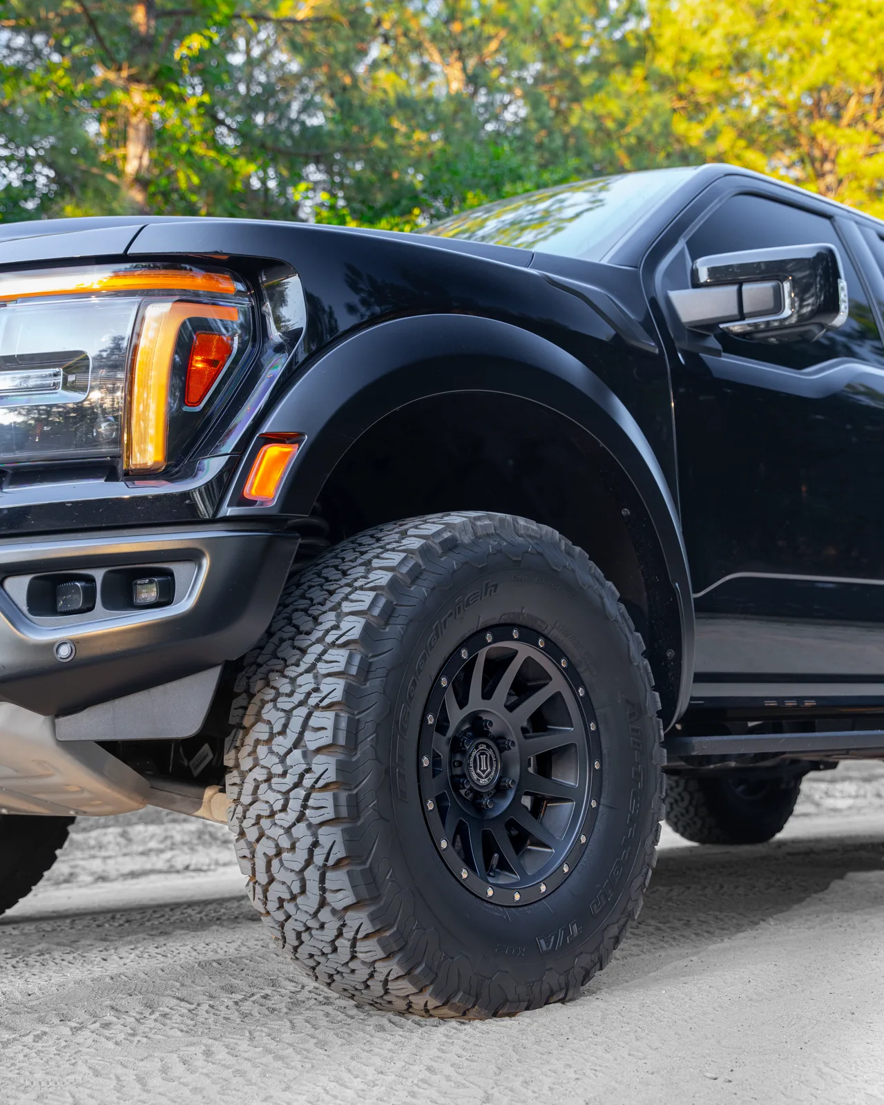 Close-up of a Ford Raptor's front wheel and off-road tire on a gravel trail